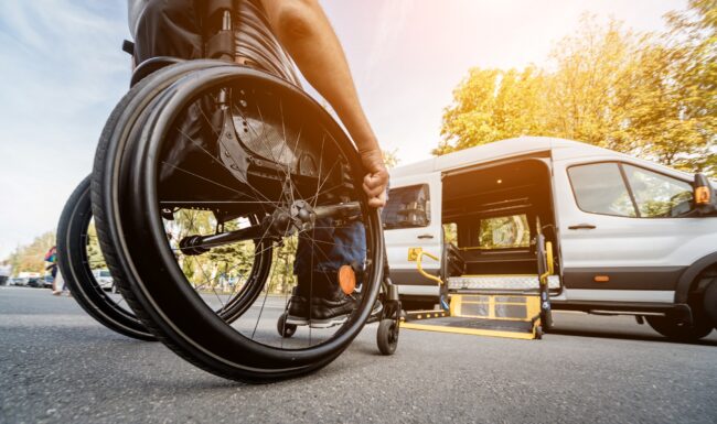 A man in a wheelchair moves to the lift of a specialized vehicle for people with disabilities